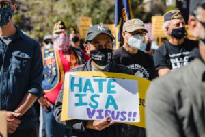 A man holding a sign at a rally that says, 'hate is a virus'. 