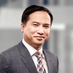 Portrait of Edward Fan in Business wear featuring a grey blazer, a checkered red tie, and a white button-up.